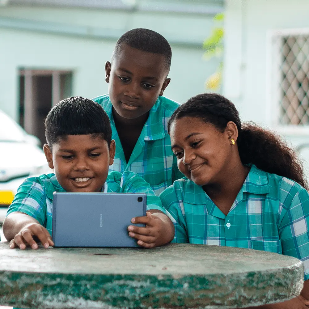 Drie kinderen op school kijken naar een tablet